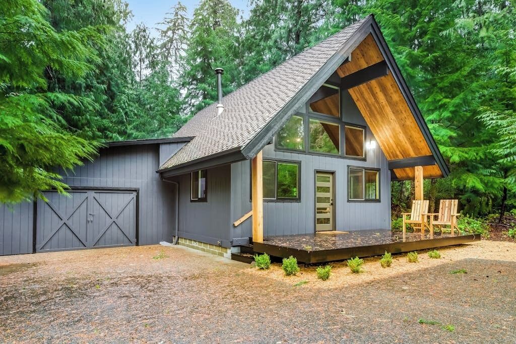 A modern cabin with a sloped roof, large windows, and a wooden deck.