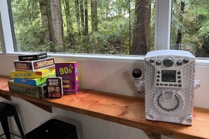 A wooden shelf with board games and a white electronic device with a speaker grille. - Alderbrook A-Frame - Game Room - Fireplace - Deck (Union)