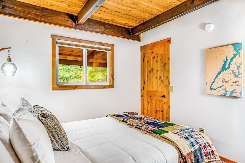Un dormitorio con una cama, una ventana, una puerta de madera y un mapa en la pared.