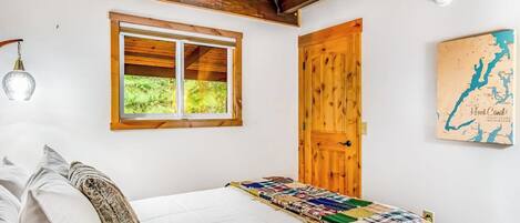 A bedroom with a bed, a window, a wooden door, and a map on the wall.