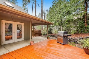 A wooden deck with a barbecue grill, a covered patio area, and a stone wall. - 3BR Golf Course View (Allyn)