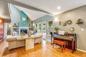Una sala de estar con un piano, una chimenea y un sofá.