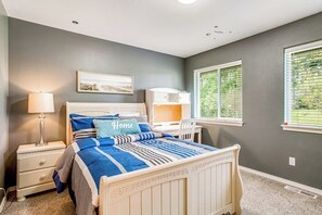 A bedroom with a bed, bedside table, lamp, and a window with blinds. - 3BR Golf Course View (Allyn)
