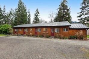 Une cabane en bois avec une allée en gravier et une porte rouge.