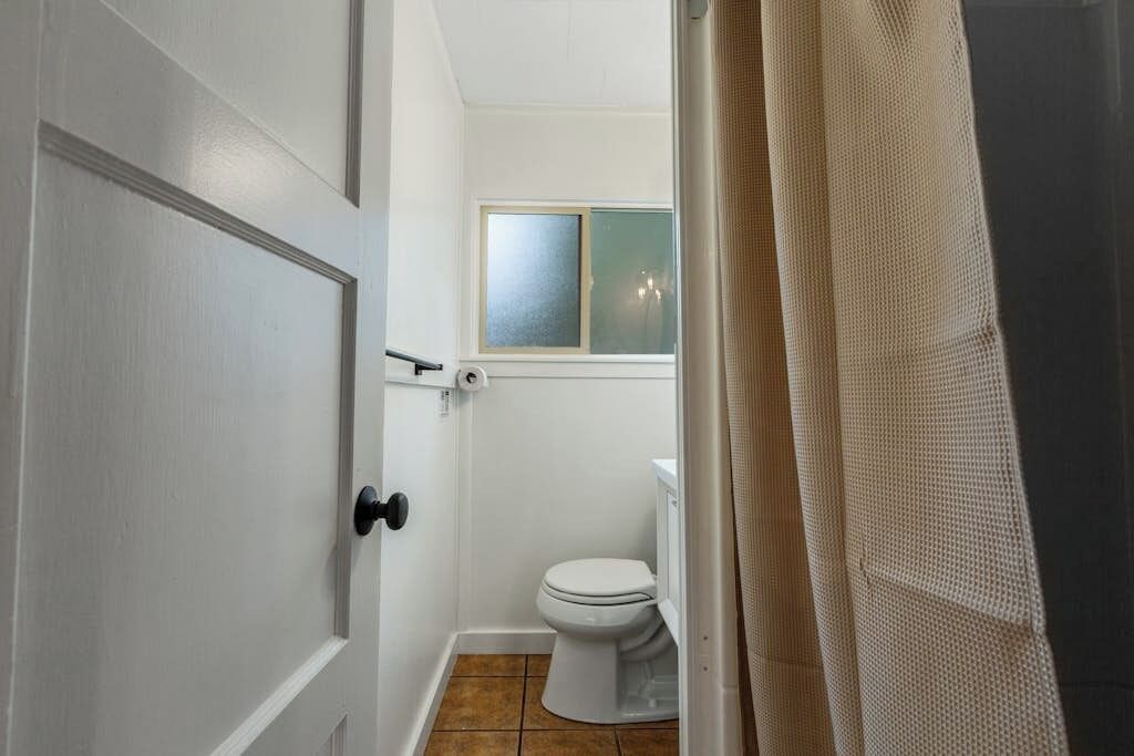 Une salle de bain avec des toilettes, une fenêtre et une porte.