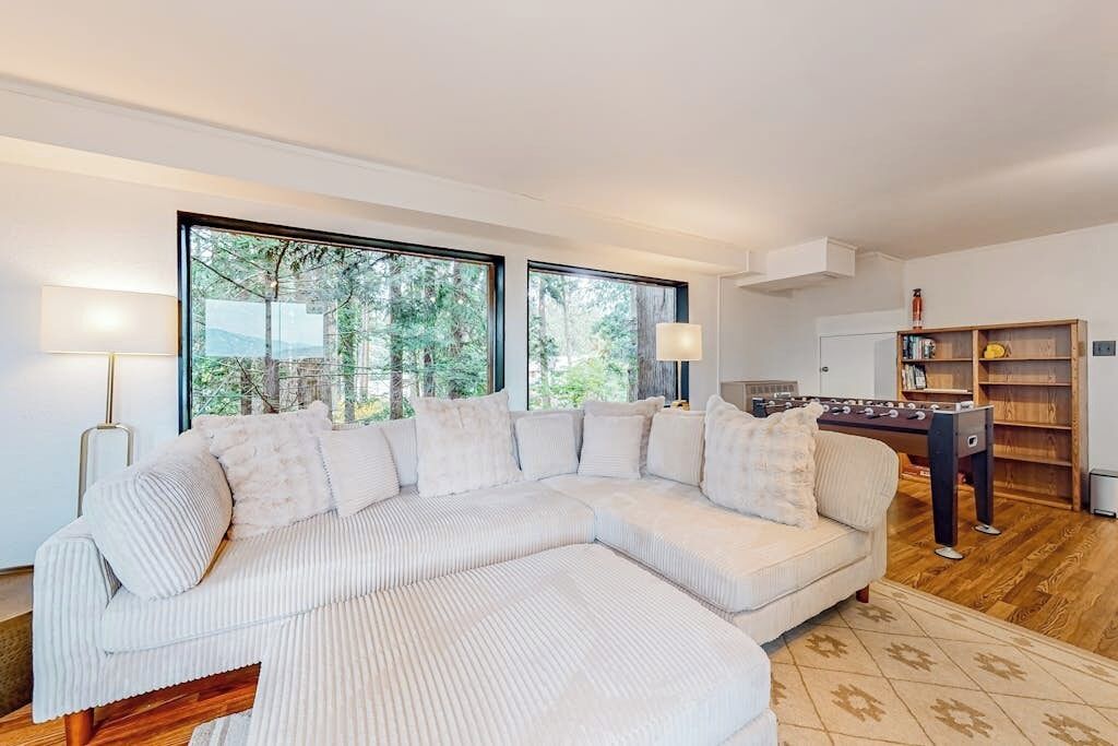 A modern living room with a large sectional sofa, a foosball table, and a bookshelf.