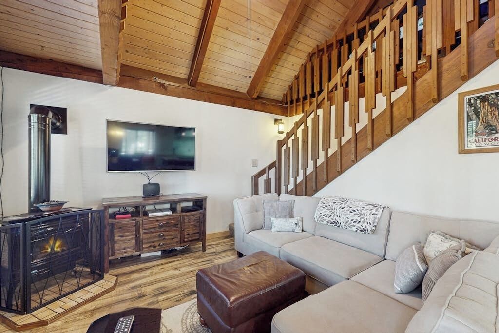 Een woonkamer met een open haard, een televisie, een bank en een trap.