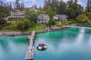 A residential area with a dock extending into a turquoise lake, surrounded by houses and lush greenery. - Waterfront Home Nearby Island Paradise (Gig Harbor)