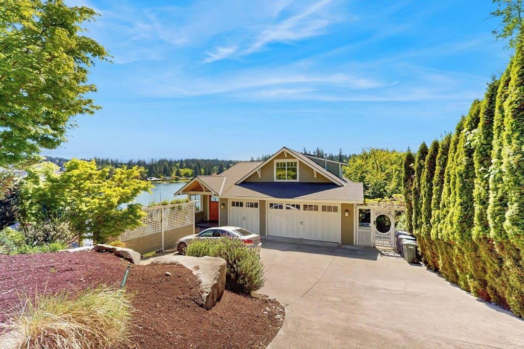Une maison à deux étages avec un garage, une allée et une vue sur un lac.