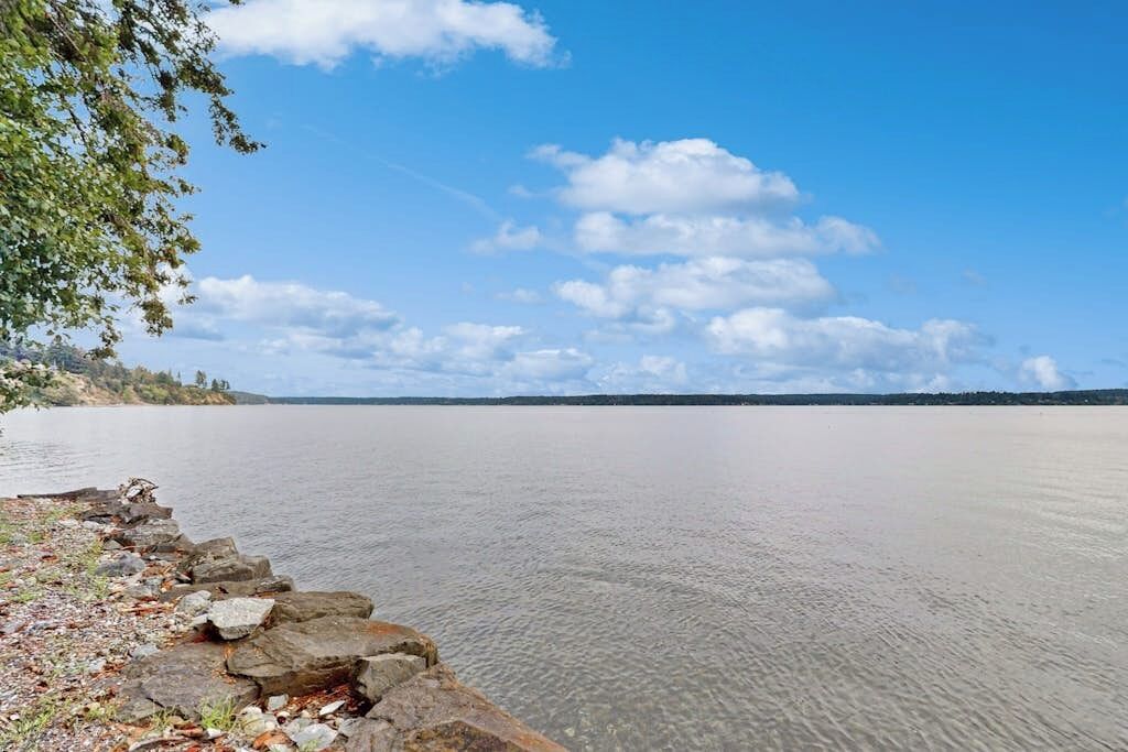 Un lago tranquilo con una orilla rocosa y un cielo despejado.