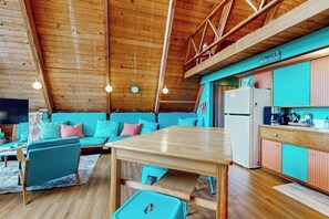 A cozy cabin interior with a wooden ceiling, a dining table, teal-colored seating, and a kitchenette. - 1BR with loft escape with expansive deck, gas grill (Gig Harbor)