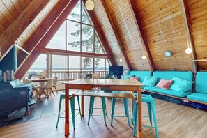 Una habitación con techos altos, interior de madera, un ventanal grande y un sofá color turquesa.