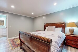 A bedroom with a wooden bed, a nightstand, a lamp, and a small drawer unit.