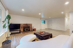 A living room with a fireplace, a television, and a large window.