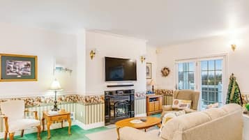 A living room with a fireplace, a television, a sofa, and a chair.