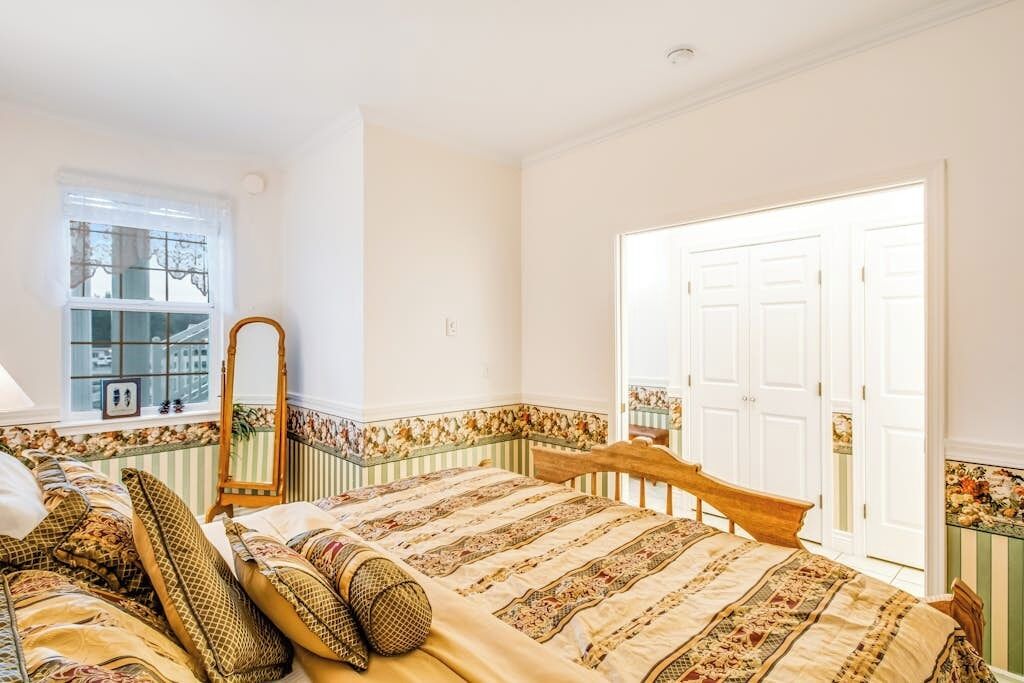 Een slaapkamer met een bed, een spiegel, een raam en een deur.