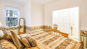 Een slaapkamer met een bed, een spiegel, een raam en een deur.