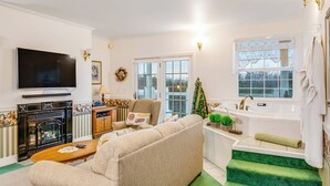 Een woonkamer met een bank, een televisie, een open haard en een groen tapijt.