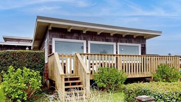 A modern house with a wooden deck, a covered porch, and a well-maintained garden.