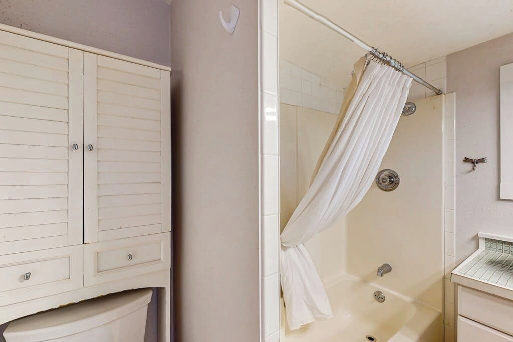 Ein Badezimmer mit Dusche, Waschtisch mit Spiegel und einem Kleiderschrank.