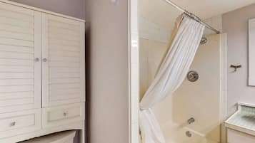 Ein Badezimmer mit Dusche, Waschtisch mit Spiegel und einem Kleiderschrank.
