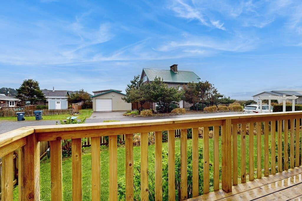 A residential area with a wooden deck, houses with green roofs, and a clear sky.