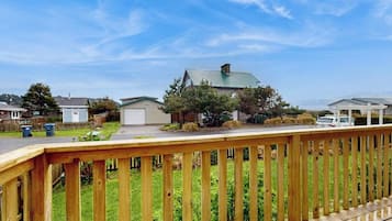 A residential area with a wooden deck, houses with green roofs, and a clear sky.