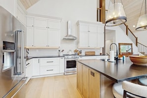 Een moderne keuken met witte kasten, roestvrijstalen apparatuur en een houten eiland.