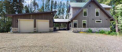 A two-story house with a gravel driveway, garage, and a stone foundation.