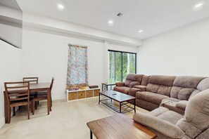 Een moderne woonkamer met een bank, eettafel en stoelen.