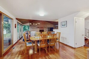 A dining area with a wooden table and chairs, a brick wall, and a staircase leading to another level. - 3BR Home on the Hood Canal with beach access & views (Poulsbo)