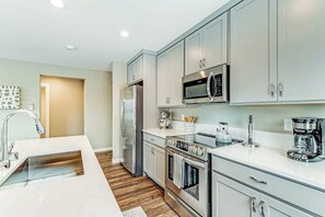 A modern kitchen with stainless steel appliances, white cabinetry, and a central island.