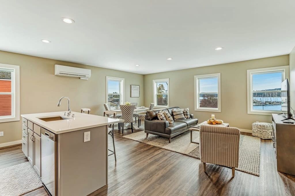 A spacious living area with a kitchen island, a sofa, and a view of the outdoors.