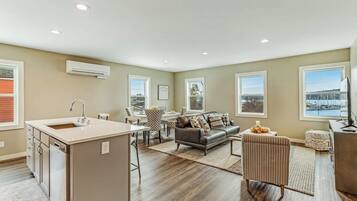 A spacious living area with a kitchen island, a sofa, and a view of the outdoors.