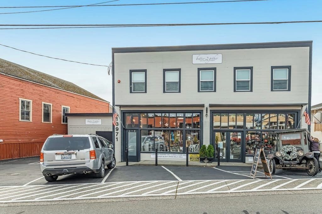 A building with a storefront, a parking lot, and a vintage car.