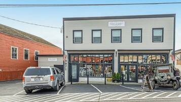 A building with a storefront, a parking lot, and a vintage car.