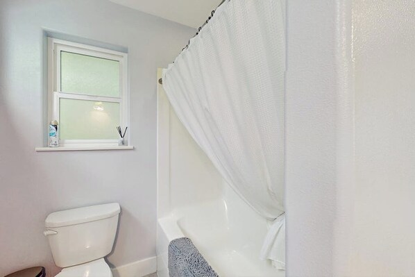Un baño con inodoro, ventana y bañera.