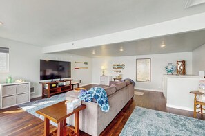 Ein Wohnzimmer mit einer Couch, einem Fernseher, einem Holztisch und einem gemusterten Teppich.