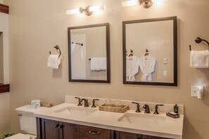 A bathroom with two mirrors, a sink with multiple faucets, and a toilet.