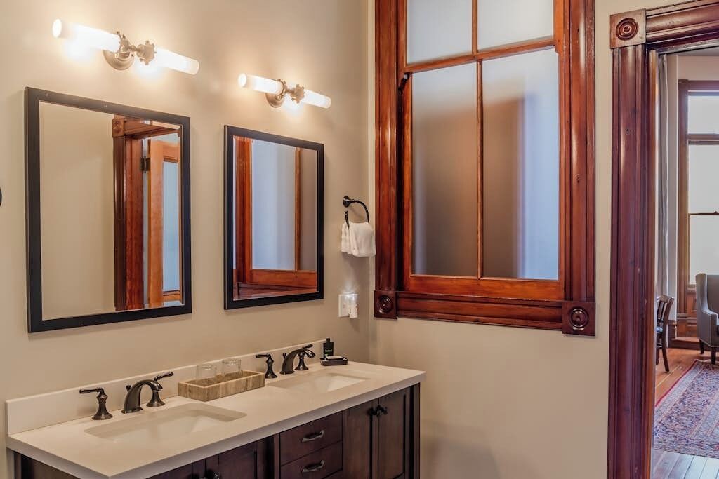 A bathroom with two sinks, a mirror, and a window.
