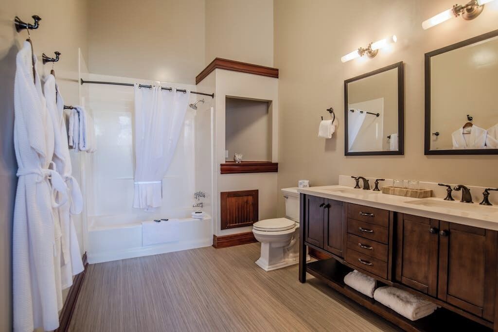 A bathroom with a bathtub, toilet, vanity with drawers, and a mirror.