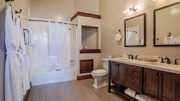 A bathroom with a bathtub, toilet, vanity with drawers, and a mirror.