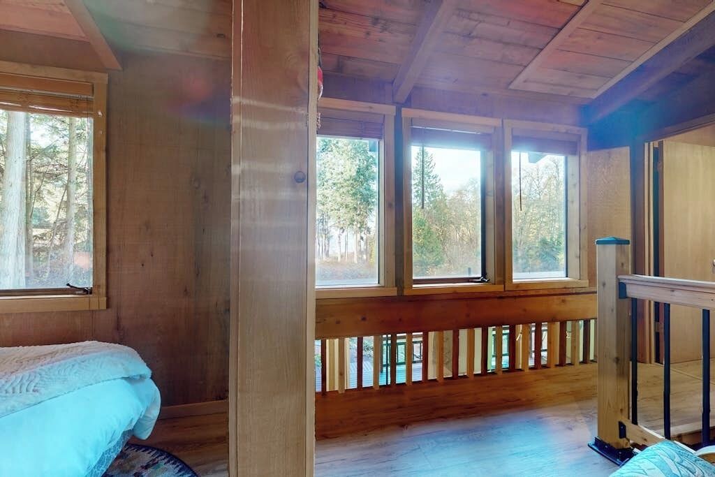 Een houten kamer met een bed, een raam en een houten leuning.