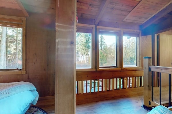 A wooden cabin room with a bed, a window, and a wooden railing. - 2 BR cabin with Hood Canal views (Hansville)