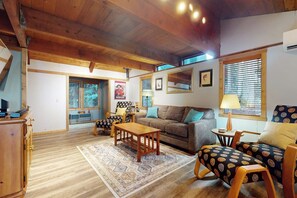 A cozy living room with a wooden ceiling, a sofa, patterned armchairs, a coffee table, and a rug. - 2 BR cabin with Hood Canal views (Hansville)