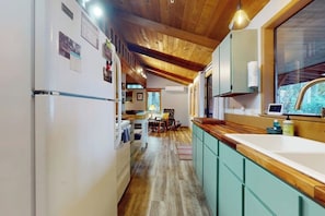 A kitchen with wooden ceiling beams, a large window, and a view of the outdoors. - 2 BR cabin with Hood Canal views (Hansville)