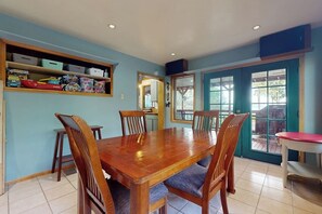A dining area with a wooden table and chairs, a shelf with toys, and a door leading outside. - 2 BR cabin with Hood Canal views (Hansville)