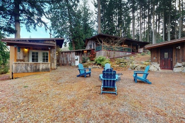 A cabin with a gravel driveway, two Adirondack chairs, and a wooden deck. - 2 BR cabin with Hood Canal views (Hansville)