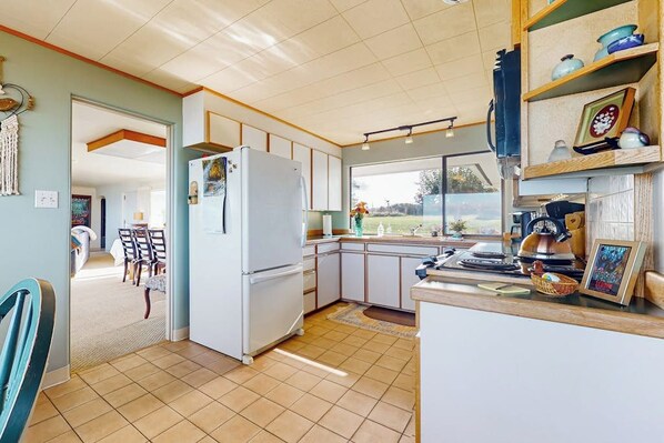 Una cocina con refrigerador, armarios y ventana con vista a un jardín.
