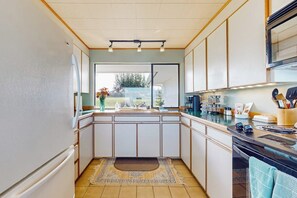A compact kitchen with a large window, a built-in oven, and a countertop with various appliances.
